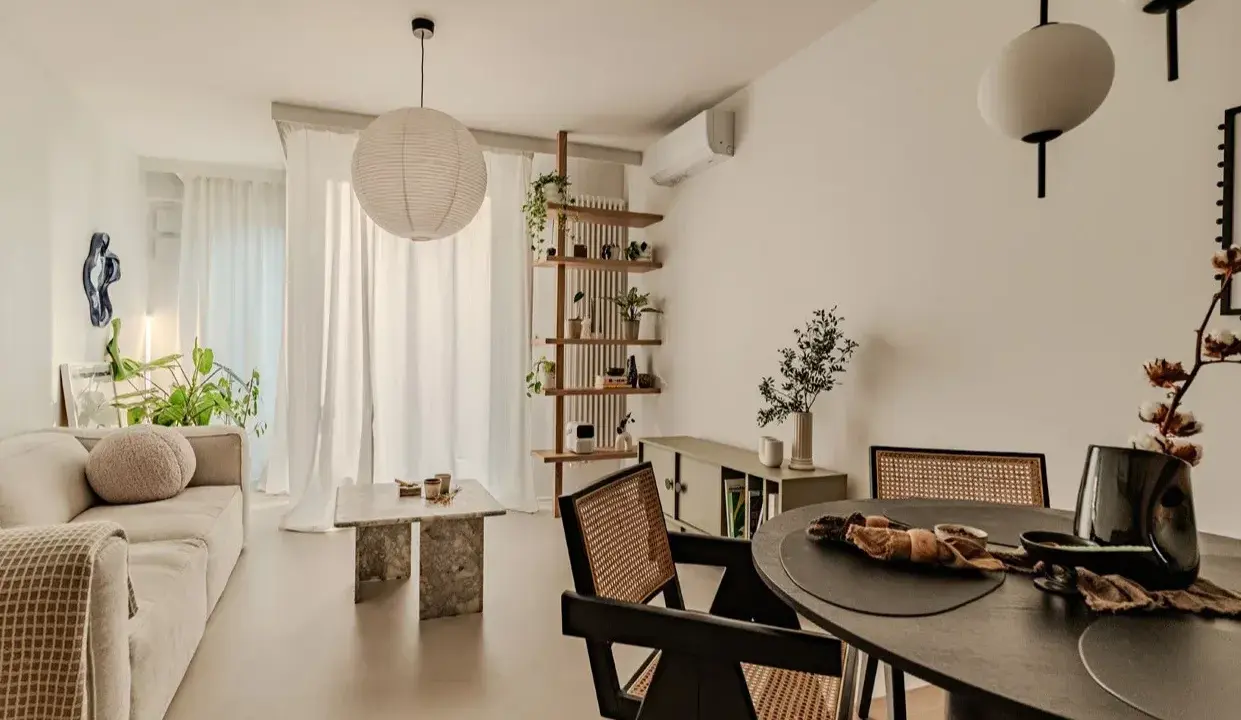 Salon w stylu japandi z beżową sofą, kamiennym stolikiem i drewnianymi meblami.