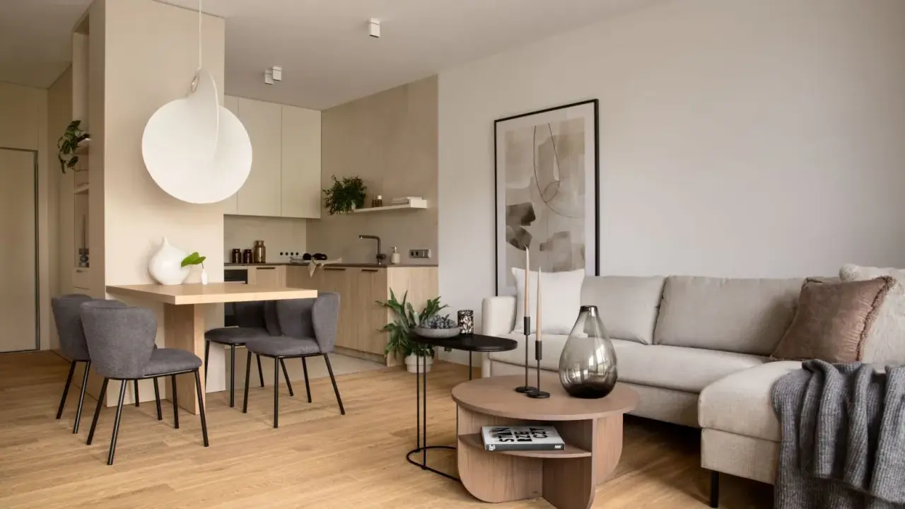 Nowoczesna jadalnia inspiracje: minimalistyczny stół z szarymi krzesłami, obok kuchnia i salon z beżową kanapą.