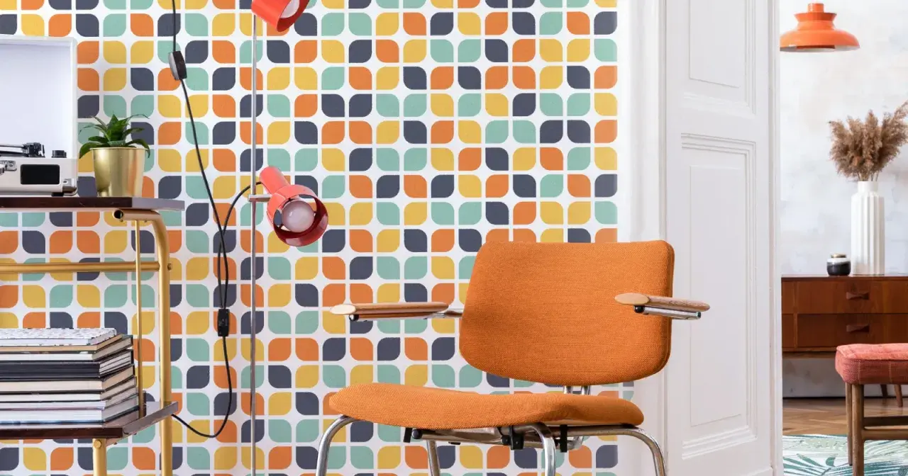 Pomarańczowe krzesło i lampa na tle tapety z geometrycznym wzorem w stylu retro.