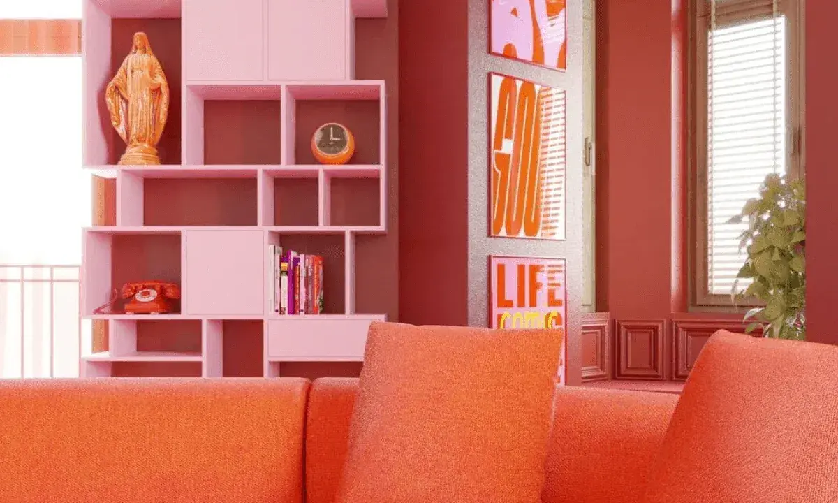 Pomarańczowa kanapa i różowe regały tworzą radosny, **dopamine decor**. Na półce figurka, telefon i zegar. Obok plakaty z napisami.