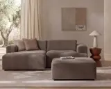 Przytulny salon z sofą i pufą w odcieniu greige, ozdobiony subtelnymi dodatkami i widokiem na drzewa oliwne.