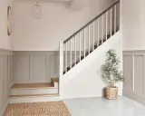 Elegancka boazeria angielska inspiracje: hol z jasną klatką schodową, drewnianymi stopniami i lustrem.