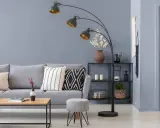Przytulny salon z szarą kanapą, stolikiem kawowym i łukową lampą. Ciepły szary kolor ścian tworzy relaksującą atmosferę.