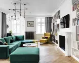 Elegancki salon w stylu paryskim z zieloną kanapą, żółtym fotelem i regałami pełnymi książek.
