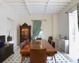 Elegancki salon w stylu kolonialnym z drewnianym stołem, witryną i zdobioną skrzynią.