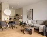 Nowoczesna jadalnia inspiracje: minimalistyczny stół z szarymi krzesłami, obok kuchnia i salon z beżową kanapą.