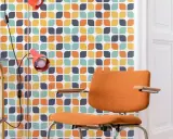 Pomarańczowe krzesło i lampa na tle tapety z geometrycznym wzorem w stylu retro.