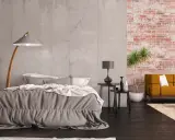 Nowoczesna sypialnia z betonową ścianą i fragmentem z tapetą szara cegła. Wygodne łóżko, kanapa i stylowe lampy tworzą przytulną atmosferę.