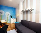 Jasne, oto propozycja:

Salon z fototapetą z dmuchawcami i asymetryczne pasy na ścianie tworzą przytulną atmosferę.