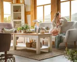 Przytulny salon w wiejskim stylu z kobietą pijącą kawę i podziwiającą widok.