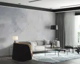 Nowoczesny salon z sofą, stolikami i fotelem. Ściana ozdobiona tapetą szary beton nadaje wnętrzu industrialny charakter.