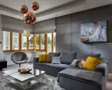 Nowoczesny salon z betonową ścianą. Inspiracje dla odważnych: szara sofa, miedziane lampy i geometryczne meble tworzą industrialny klimat.