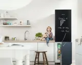 Chłopiec z pluszowym psem siedzi na blacie w kuchni, jedząc lody. Obok lodówka z tablicą, na której mama napisała "There's an ice cream for you here". Inspiracje na tablicę w kuchni.