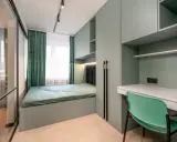 Nowoczesny styl sypialni z łóżkiem, biurkiem i szafami w odcieniach zieleni. Wygodne miejsce do odpoczynku i pracy.