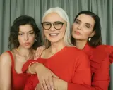 Trzy kobiety w czerwonych strojach, otoczone złotą biżuterią, tworzą piękny kontrast do złotego koloru.