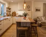 Przytulna kuchnia modern farmhouse z drewnianą wyspą, białymi meblami i ciepłym oświetleniem.