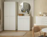 Nowoczesny przedpokój z tapetą w kratę, białe meble, lustro i płaszcz na wieszaku.