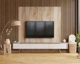 Nowoczesny salon z telewizorem na tle pionowych lamelek. Drewniana okładzina i meble tworzą przytulną atmosferę.