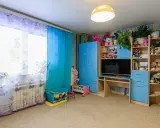 Pokój dziecięcy w stylu lat 90. z niebieskimi meblami, pluszakami i kolorowymi zasłonami.