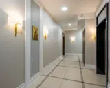 Elegancki korytarz z oświetleniem ściennym i numerem 7. Widać windę i drzwi. Czy ten pasek pod sufitem jest potrzebny?