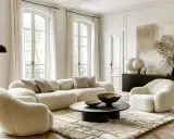 Przytulny, **modern classic salon** z puszystymi meblami, okrągłym stolikiem i sztuką abstrakcyjną.