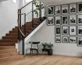 Nowoczesna ściana przy schodach inspiracje: galeria czarno-białych zdjęć architektonicznych i krajobrazowych, drewniane schody, czarne balustrady i krzesło.