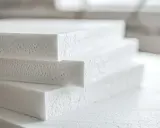 Stos białych płyt styroduru, idealnych do izolacji. Zastanawiasz się, czym kleić styrodur? Ten materiał wymaga specjalistycznych klejów.