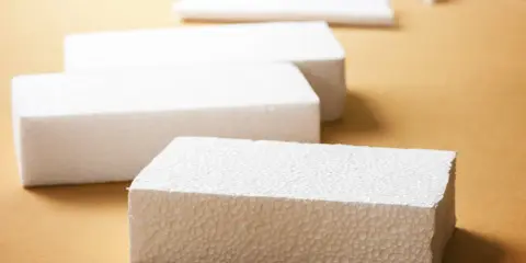 Białe bloki styropianu na brązowym tle. Idealne do wypełniania dziur w styropianie lub jako materiał do rękodzieła.