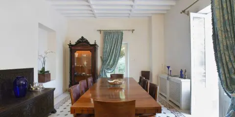 Elegancki salon w stylu kolonialnym z drewnianym stołem, witryną i zdobioną skrzynią.