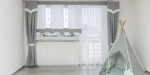 Szare zasłony w gwiazdki i białe firanki idealnie pasują na okno do pokoju młodzieżowego. Obok namiot tipi.