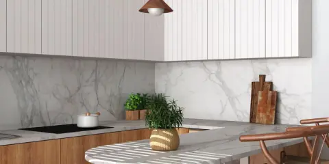 Elegancka styl japandi kuchnia z drewnianymi frontami, marmurowym blatem i minimalistycznymi białymi szafkami. Dwa drewniane krzesła barowe.