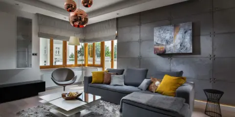 Nowoczesny salon z betonową ścianą. Inspiracje dla odważnych: szara sofa, miedziane lampy i geometryczne meble tworzą industrialny klimat.