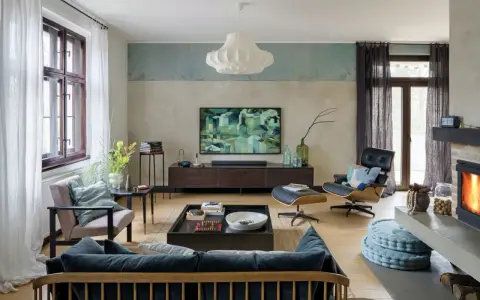 Nowoczesny salon z wygodną kanapą i fotelem. Abstrakcyjny obraz na ścianie dodaje charakteru.