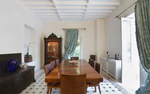 Elegancki salon w stylu kolonialnym z drewnianym stołem, witryną i zdobioną skrzynią.