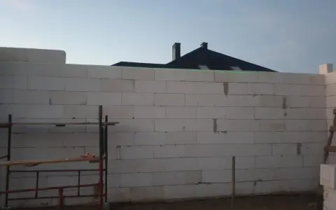 Budowa domu z bloczków, zielona linia laserowa wyznacza poziom. To dobry pomysł na krzywe ściany, jeśli chcesz uzyskać ciekawy efekt architektoniczny.