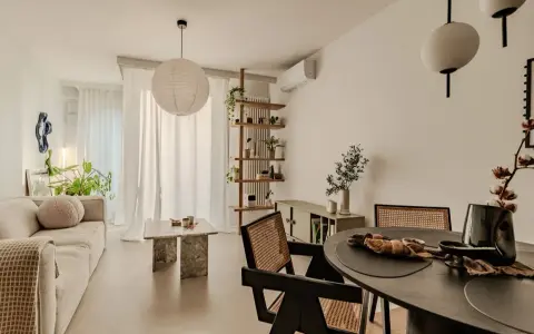 Salon w stylu japandi z beżową sofą, kamiennym stolikiem i drewnianymi meblami.