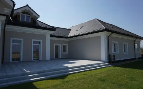 Nowoczesny dom z tarasem i trawnikiem. Elegancki gzyms co to? To ozdobny element architektoniczny podkreślający linię dachu.