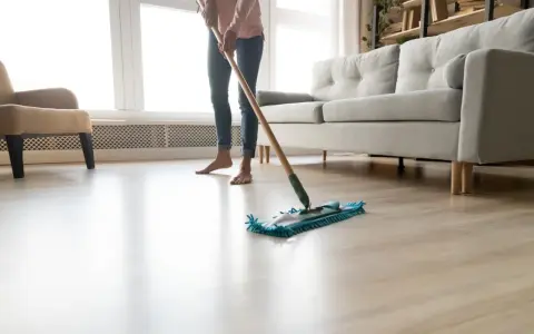 Osoba myje podłogę mopem, zastanawiając się, czym myć panele plastikowe.