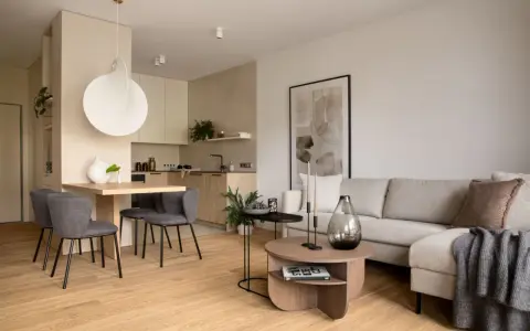 Nowoczesna jadalnia inspiracje: minimalistyczny stół z szarymi krzesłami, obok kuchnia i salon z beżową kanapą.