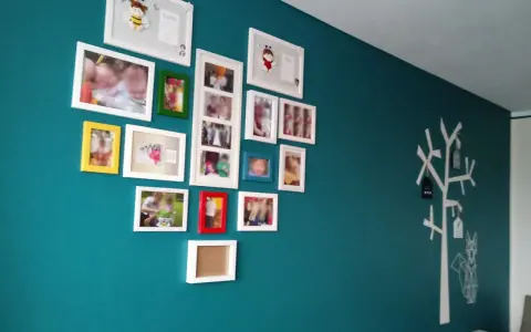 Galeria zdjęć na turkusowej ścianie, z motywem drzewa i lisa po prawej stronie.