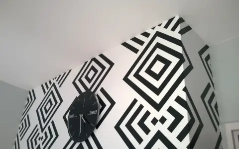 Nowoczesne tapety biało czarne z geometrycznym wzorem rombów. Zegar ścienny w czarnej ramie idealnie komponuje się z aranżacją.