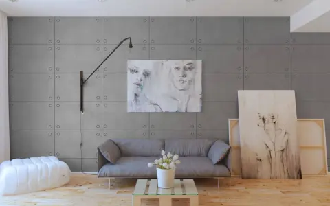 Nowoczesne wnętrze z panelami imitującymi beton. Sofa, stolik z palety, biały puf i obrazy tworzą stylową aranżację.