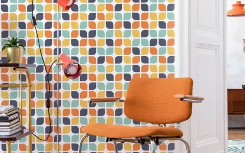 Pomarańczowe krzesło i lampa na tle tapety z geometrycznym wzorem w stylu retro.