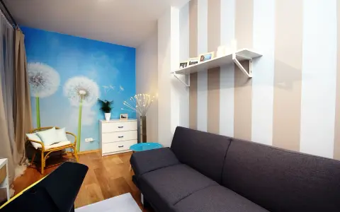 Jasne, oto propozycja:

Salon z fototapetą z dmuchawcami i asymetryczne pasy na ścianie tworzą przytulną atmosferę.