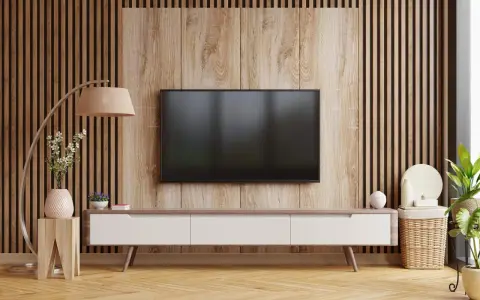 Nowoczesny salon z telewizorem na tle pionowych lamelek. Drewniana okładzina i meble tworzą przytulną atmosferę.