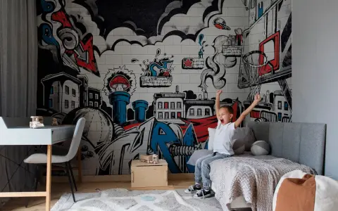 Chłopiec cieszy się w pokoju z dynamicznym **graffiti w pokoju** na ścianie, przedstawiającym miasto i elementy koszykówki.