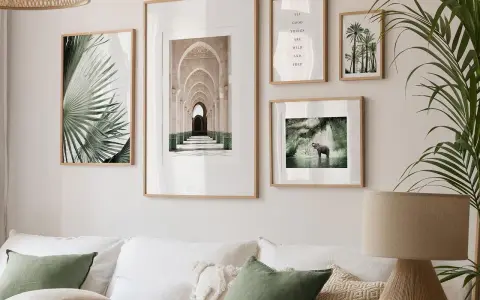 Inspiracja, jak wieszać obrazy nad kanapą: liście palmy, arkady, cytat i słoń w wodzie tworzą galerię ścienną.