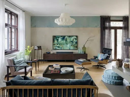 Nowoczesny salon z wygodną kanapą i fotelem. Abstrakcyjny obraz na ścianie dodaje charakteru.