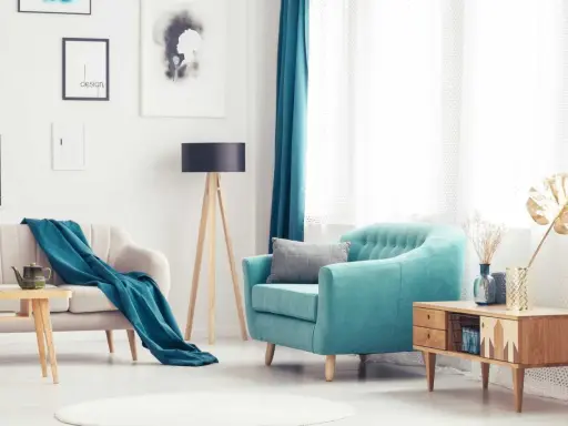 Turkusowy fotel i pled na kanapie tworzą przytulną atmosferę w salonie.