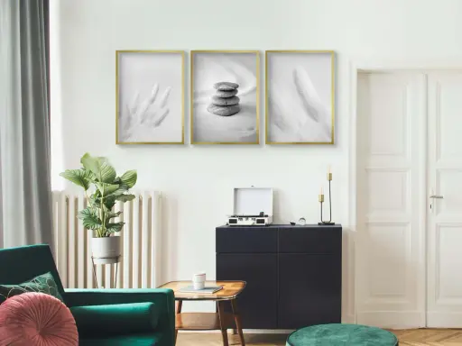 Trzy minimalistyczne plakaty w złotych ramach nad ciemną komodą. Dowiedz się, jak powiesić plakat bez niszczenia ścian.